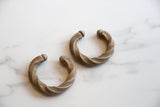 A pair of antique African aluminum cuffs showing their twisted, hand-worked design.