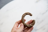 Antique twisted aluminum cuff held in a hand, showing its handcrafted texture and scale.