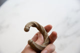 The sculptural form and twisted pattern of an antique aluminum African cuff held in hand.