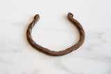 Twisted copper body and curled, pierced ends of an antique African cuff bracelet.