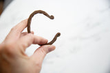 A hand holding the antique African copper cuff to show its twisted form and scale.