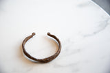 Close-up showing the antique African iron bracelet's hand-twisted band and scrolled ends.