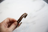 Hand holding the antique African iron bracelet with double twisted design and aged patina.