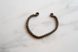Top view of an antique African bracelet showing its twisted copper and curled ends.