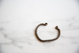 Twisted design and dark patina of an antique African copper alloy bracelet.