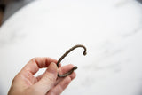 Antique African copper alloy bracelet held to show its handcrafted twisted shape and scale.