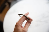 The tactile twisted design of an antique African copper alloy bracelet held in hand.