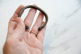 The antique bronze cuff bracelet held in hand to show its scale and handmade form.
