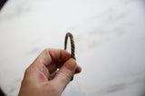 Collectible antique copper cuff with a twisted design held in hand to show scale.