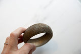 Detailed view of the intricate floral engraving and oxidized texture on the antique bronze bracelet.