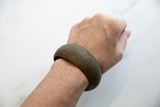 Antique African bronze bracelet with etched florals worn on a wrist.