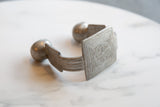 Detailed craftsmanship shown in the geometric etchings on an antique aluminum cuff.