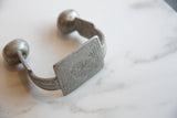 Hand-etched geometric design on the central panel of the antique aluminum cuff.
