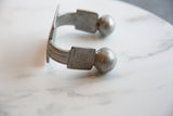 Close view of the etched geometric pattern and spherical end on an antique aluminum cuff.