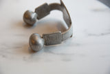 Aged patina and etched geometric design on the antique African aluminum cuff's terminal.