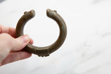 Antique African bronze cuff held to show its curved form and textured patina.