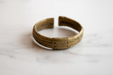 Angled view of an antique bronze cuff highlighting its open ends and textured patina.