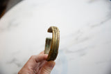 Profile view of an antique African bronze cuff showing its stripe design and aged patina.