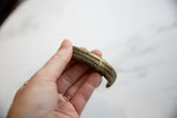 Holding the antique African cuff to display its striped detail and bronze patina.
