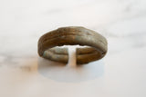 The textured, oxidized bronze surface and open ends of an antique African cuff bracelet.