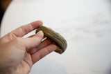 Antique bronze cuff bracelet held in hand, showing its scale and etched stripe design.
