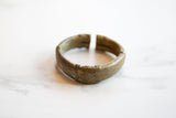 The substantial, rounded form and aged bronze patina of a handmade African cuff bracelet.