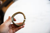 Hand holding the antique bronze alloy cuff to show its scale and time-softened patina.