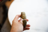Open ends of a handmade antique African bronze cuff bracelet held for scale.