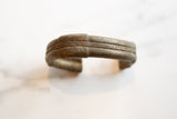 Detailed view of the antique bronze cuff's hand-worked stripe and braided texture.