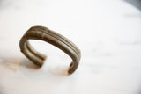 Angled view showing the handcrafted stripe detail on the antique bronze cuff.