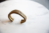 The open C-shape and rustic striped design of the antique African bronze cuff.