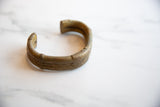 Handcrafted texture and golden patina on the surface of an antique bronze cuff bracelet.