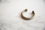 Antique African aluminum cuff showing its open C-shape and rustic, time-worn patina.