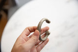 Antique aluminum snake cuff held in hand to show its scale and hand-worked surface.