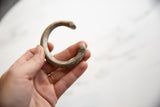 Antique African snake cuff bracelet held in hand, showing its rustic, aged texture.