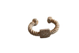 Antique African aluminum cuff bracelet with a twisted design and a central square with geometric detailing.
