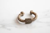 The twisted aluminum body and etched geometric detail of an antique African cuff bracelet.