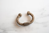 Angled profile of an antique African cuff bracelet with twisted aluminum and etched details.