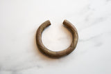 The distinctive open cuff and spiraling barber pole design of an antique bronze bracelet.