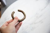 Antique bronze and copper bracelet held in hand, showing scale and surface texture.