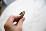 Hand-held view of the antique bronze bracelet highlighting its aged, textured surface.
