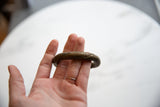 Antique bronze African bracelet held in hand, showing its aged patina and curve.