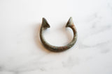 Textured bronze alloy and time-softened patina on one end of the antique African manilla.