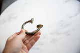 Antique African bronze manilla cuff bracelet held in hand, showing fine craftsmanship.