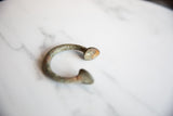 Antique African bronze alloy manilla cuff bracelet end with visible texture and historic patina.