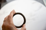 Hand-held antique African bronze alloy bracelet, highlighting its textured, time-softened surface.