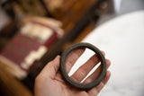 Patinated surface texture of the antique African bronze bracelet, held in hand.
