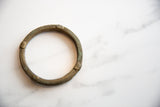 Antique bronze bracelet with geometric carvings showing its time-worn surface texture.