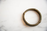 Overhead view of an antique African bronze bracelet's circular shape and etched, time-softened patina.