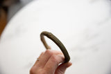 Close view of the ribbed geometric texture and aged patina on the antique bronze bracelet.